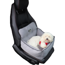 Hvid bomuldshund ligger i en grå hundeautostol, som står på et sort bilsæde